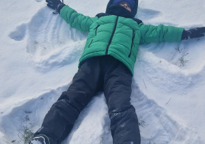 Chłopiec robi aniołka na śniegu