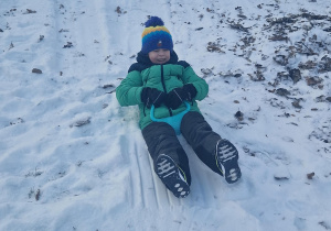 Chłopiec zjeżdża z zaśnieżonej górki