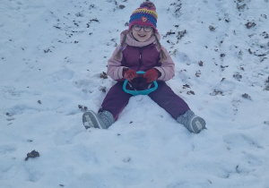 Dziewczynka zjeżdża z zaśnieżonej górki