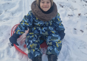 Chłopiec zjeżdża z zaśnieżonej górki