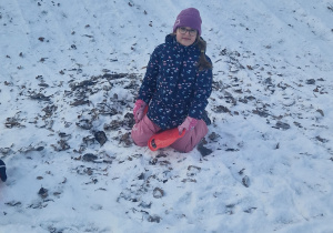 Dziewczynka zjeżdża z zaśnieżonej górki