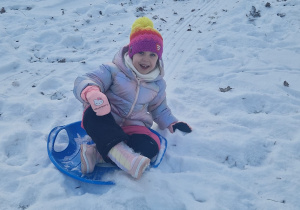 Dziewczynka zjeżdża z zaśnieżonej górki