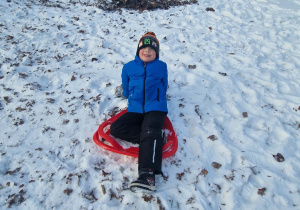 Chłopiec zjeżdża z zaśnieżonej górki