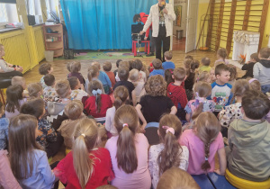 Pan w białej marynarce wita dzieci przez mikrofon