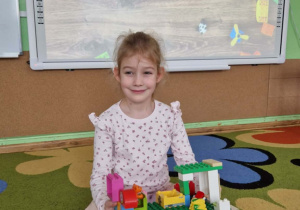 Dziewczynka prezentuje swoją budowlę z klocków lego