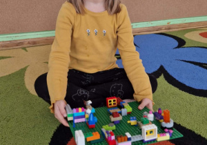 Dziewczynka prezentuje swoją budowlę z klocków lego