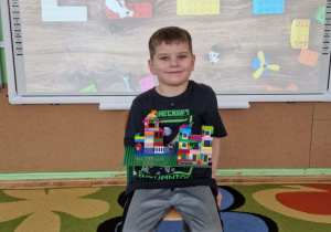 Chłopiec prezentuje swoją budowlę z klocków lego