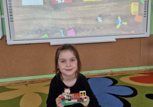 Dziewczynka prezentuje swoją budowlę z klocków lego