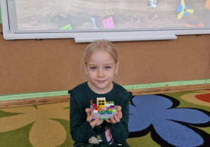 Dziewczynka prezentuje swoją budowlę z klocków lego