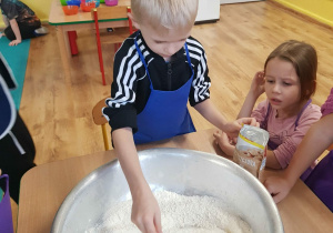 Chłopiec miesza mąkę w misce