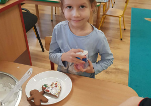 .Dziewczynka dekoruje piernik lukrem i posypką.