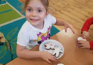 .Dziewczynka dekoruje piernik lukrem i posypką.