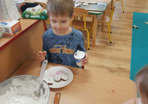 Chłopiec dekoruje pierniki lukrem i posypką