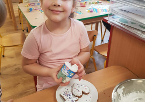 .Dziewczynka dekoruje piernik lukrem i posypką.