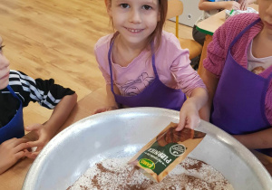 Dziewczynka dodaje przyprawę do piernika do mąki.