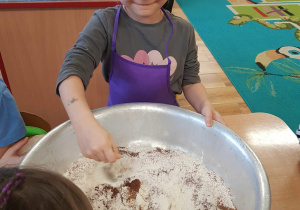 Dziewczynka dodaje przyprawę do piernika do mąki.