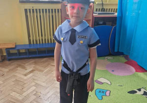Chłopiec w przebraniu policjanta pozuje doa zdjęcia