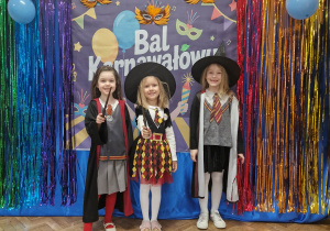 Dziewczynki w przebraniach pozują na tle dekoracji