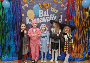 Dziewczynki w przebraniach karnawałowych pozują na tle dekoracji