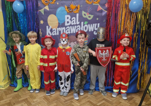 Chłopcy w przebraniach karnawałowych pozują na tle dekoracji