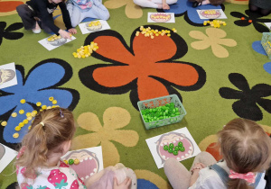 Dzieci wykonują zadania matematyczne z kolorowymi nakrętkami