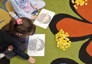 Dzieci wykonują zadania matematyczne z kolorowymi nakrętkami