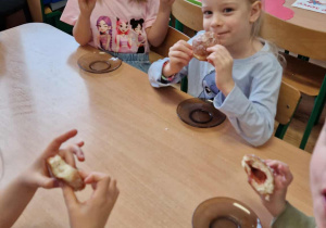 Dzieci siedzą przy stole i degustują pączki