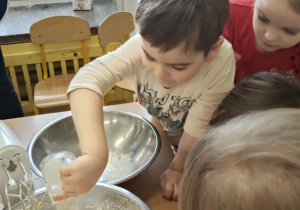 Chłopiec wsypuje mąkę do miski