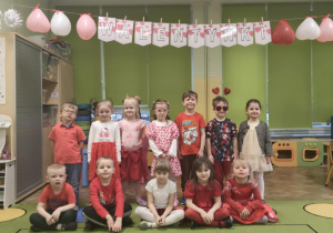 Dzieci ubrane na czerwono pod napisem Walentynki