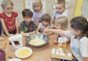 Dziewczynka wsypuje proszek do pieczenia do miski