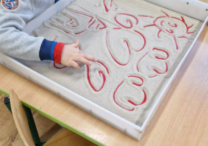 Chłopiec rysuje serca na piasku