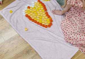 Dziewczynka układa serce z plastikowych korków