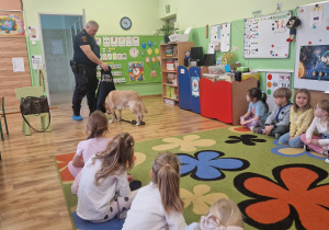 Pan strażnik Miejski prezentuje bezpieczne zachowania z psem