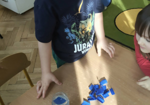 Dziecko wrzuca bibułę do słoiczka