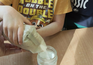 Dziecko dodaje sól do słoiczka z wodą