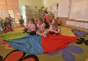 Dziewczynki siedza na kolorowej chuście czekaja na prezenty