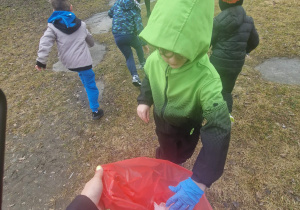 Dzieci w rękawiczkach zbieraja śmieci do worka
