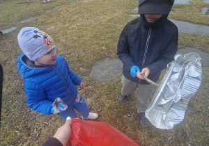 Dzieci w rękawiczkach zbieraja śmieci do worka