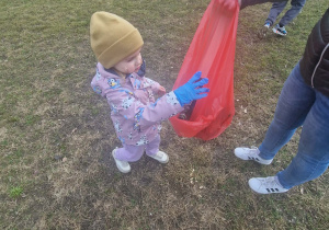 Dzieci w rękawiczkach zbieraja śmieci do worka