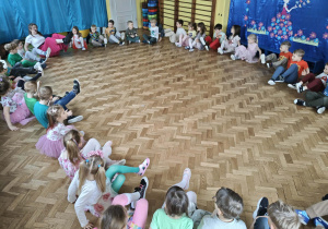 dzieci siedzą w kole i uczestniczą w zabawie