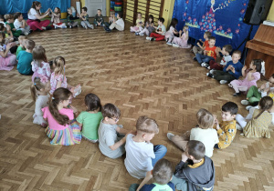 dzieci siedzą w kole i uczestniczą w zabawie
