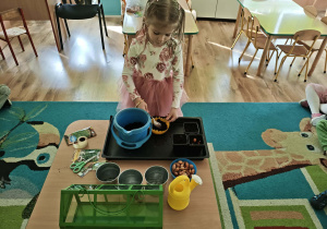 Dziewczynka nasypuje ziemię do doniczki