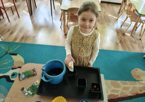 Dziewczynka nasypuje ziemię do doniczki