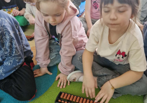 dzieci manipulują na małym liczydle