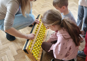 dzieci manipuluja na dużym liczydle liczydle