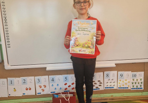 Dziewczynka prezentuje dyplom i nagrodę za zajęcie II miejsca