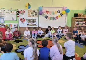 przedszkolaki słuchają czytanych bajek przez kolegów ze szkoły