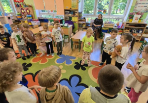 Dzieci uczestniczą w zabawie w kolory z pluszowym misiem