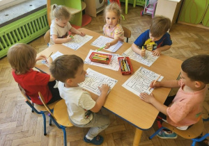 Dzieci z gr 3 układają puzzle przy stole