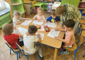 Dzieci z gr 3 układają puzzle przy stole